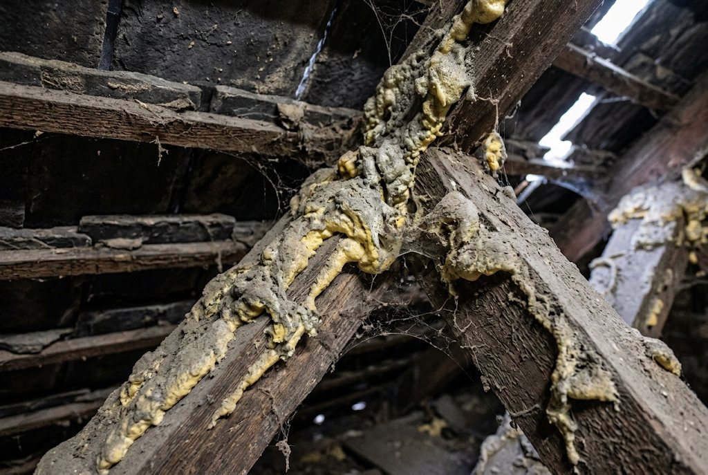 Stained timber under peeled foam in an Aspull loft.